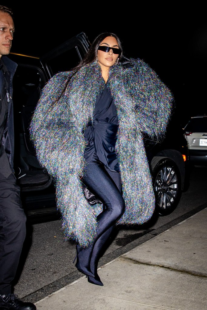 Kim Kardashian in a tight black bodysuit and a sparkly faux fur coat.
