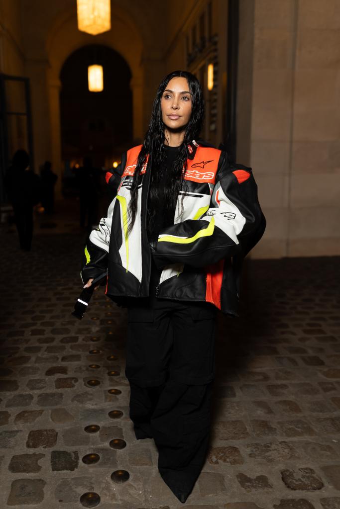 Kim kardashian in black pants and a racer jacket.